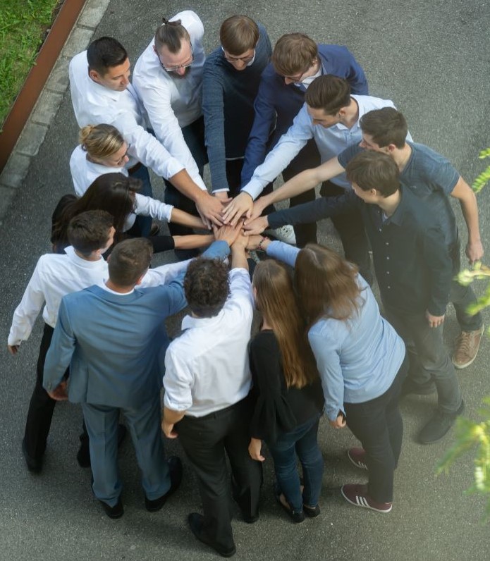 Ganzes Team steht zusammen und jeder hält die Hand in die Mitte